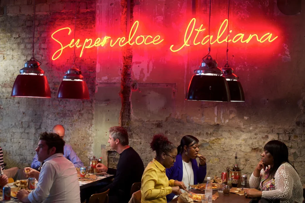 Evening diners under the Superveloce Italiana neon