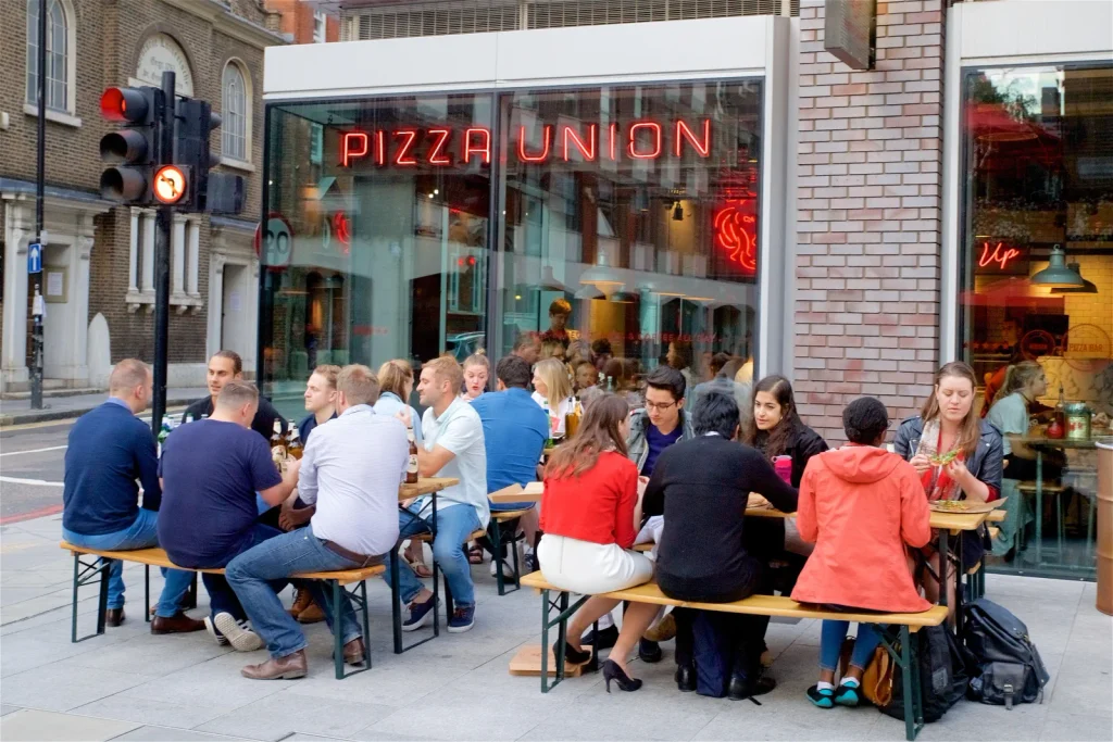 A group eating outside Pizza Union Aldgate